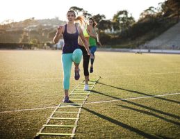 Female athletes training with agility ladder on sports field
